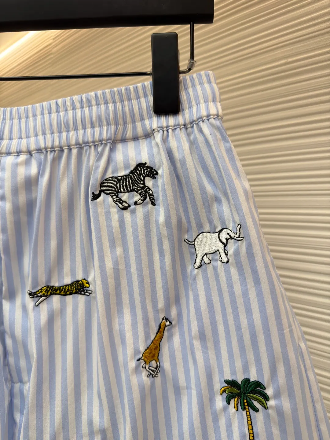 LOUIS VUITTON Animal and plant nostalgic style embroidered striped shorts ●Original version: purchased and developed by 14616 ●Item number: 1682542-A75 ●Fabric: cotton fabric ●Technology: embroidery production ●Color: blue ●Version: fitted version ●Weight: about 205 grams ●Size: S-M-L-XL ●Description: Made of high-count pure cotton poplin fabric. After pre-washing process, it feels smooth and breathable. It has both drape and stiffness, and is not easy to wrinkle and deform. The blue and white vertical stripes on the body are woven with yarn-dyed technology, and the texture is clear and does not fade. The animal and coconut tree patterns are presented with sophisticated embroidery technology. The embroidery threads are full of color and the stitches are dense. The patterns are three-dimensional and vivid, forming a rich visual hierarchy with the stripe base. The shirt has a Cuban collar style, with smooth necklines, custom mother-of-pearl buttons at the placket, and a warm texture. The overall shape is loose, the shoulder joints are straight and fine, the cuffs are cuffed with exquisite craftsmanship, custom accessories and three logos are complete, and the details are full of luxury craftsmanship. It is suitable for casual vacations and daily outings, etc. The overall wiring is straight and delicate, the fabric is comfortable and soft, and the color is consistent without color difference. It can be matched with the same style to create a fashionable look and control various occasions. Customized accessories, complete with three standards, same style for men and women!